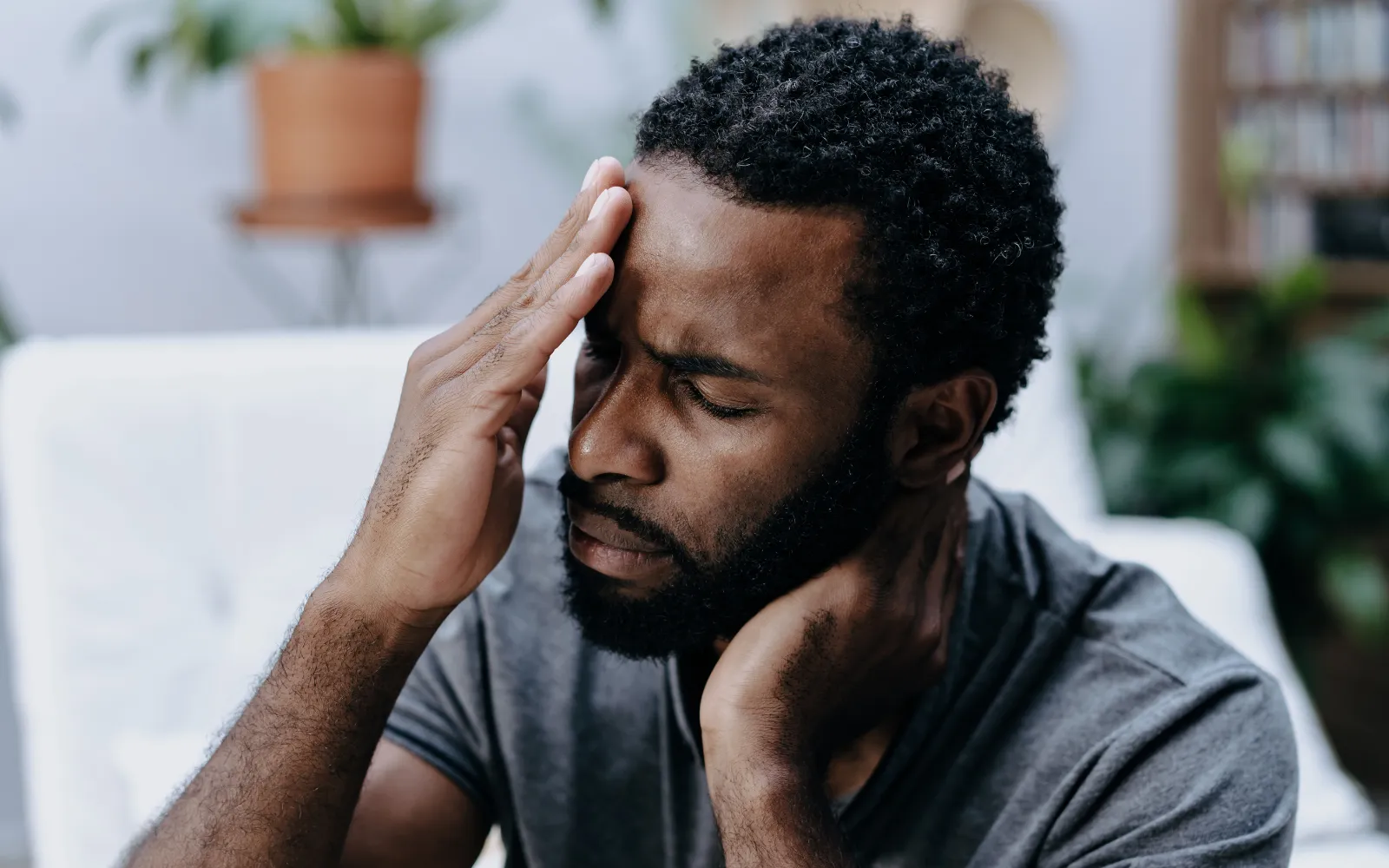 A man rubbing his forehead with a visible migraine caused by poor indoor air quality and mold toxicity